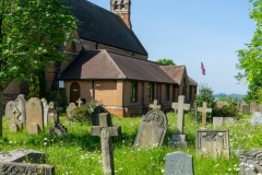 St. Mark's churchyard, showing gravestones, wildflowers and the union flag on a flagpole.